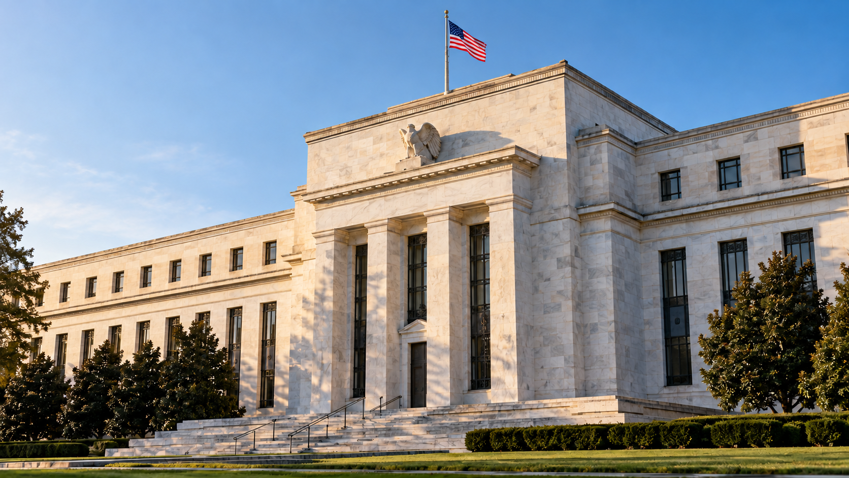 Fachada de pedra clara com colunas do Federal Reserve e bandeira dos Estados Unidos sob céu azul